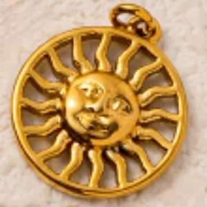 Primo piano macro dettagliato di un ciondolo a forma di sole in acciaio dorato.
