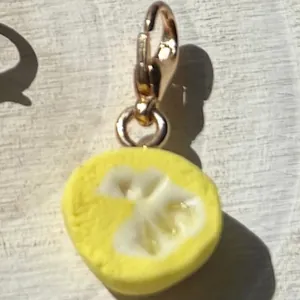 Detalle de primer plano de un dije de rodaja de limón amarillo con cierre de mosquetón