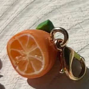 Primer plano detallado de un dije de rodaja de naranja en miniatura con cierre dorado