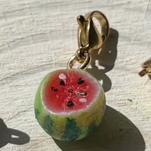 Primer plano detallado de un dije de sandía en miniatura realista con cierre dorado