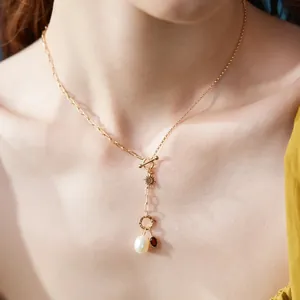 Detailed view of gold stainless steel necklace featuring a pearl and red birthstone pendant