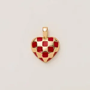 Gros plan d'un pendentif en forme de cœur avec un motif en émail rouge et or à damier.