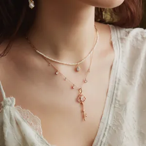 Close-up view of elegant layered pearl and rose gold key pendant necklace on a model