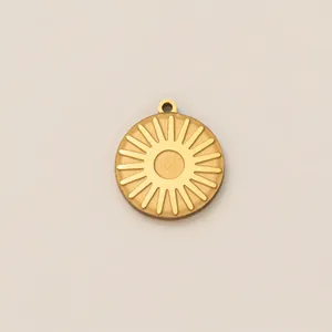 Dettaglio di un ciondolo tondo minimalista in acciaio inossidabile dorato con sole