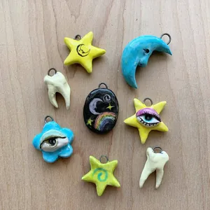 Ciondoli creativi in acciaio inox con motivi a luna, stella, occhio e dente smaltati.