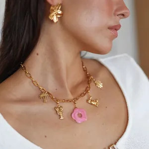 Nahaufnahme einer goldenen Charm-Halskette mit rosa Blume und sommerlichen Meeresmotiven