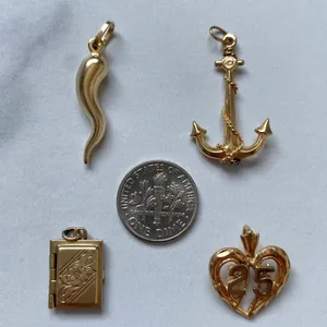 Variety of gold-plated stainless steel pendants shown next to a dime for scale.