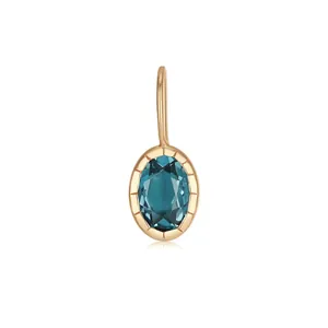 Detailed close-up view of an elegant oval golden pendant set with a deep blue teal gemstone