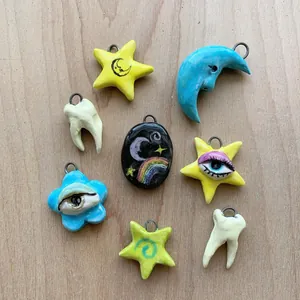 Dettaglio di ciondoli misti tra cui forme di stella luna occhio e dente colorati.