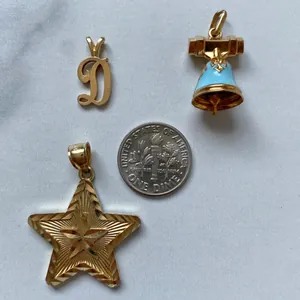Detailed view of gold stainless steel star, bell, and letter D pendants with coin for scale