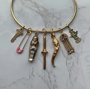 Vista dettagliata di un bracciale rigido dorato in acciaio inox con ciondoli eclettici