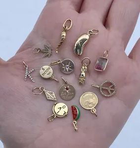 Una collezione di ciondoli in acciaio inossidabile nei toni oro e argento tenuti in mano.