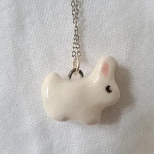 Close-up of white rabbit ceramic pendant on a silver-colored chain