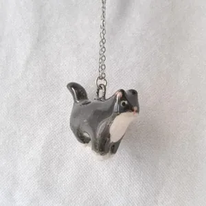 Detailed view of a cute black and white tuxedo cat pendant on a stainless steel chain