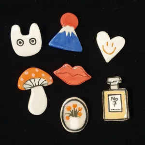Assorted colorful enamel charms featuring mushroom, heart, and perfume bottle designs