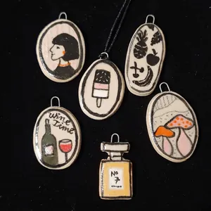 Close-up of dopamine style stainless steel enamel pendants with various artistic motifs.