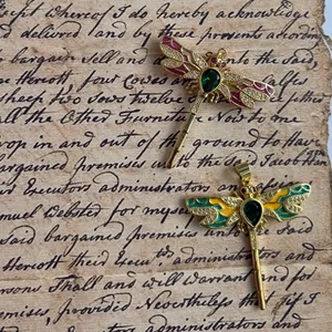 Dettaglio di ciondoli a forma di libellula stile vintage con pietre verdi e smalto