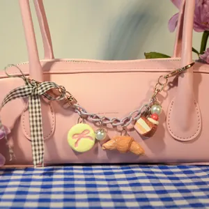Vue détaillée de cet accessoire de sac pastel avec ses pendentifs croissant et part de gâteau