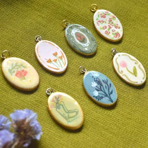 Detailansicht von ovalen Anhängern mit bunten Blumenmustern und Emaille-Finish.