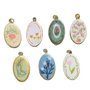 Set aus sieben ovalen Edelstahl-Anhängern mit farbenfrohen handgemalten Blumendesigns