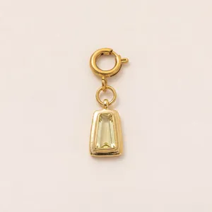 Detailopname van een vergulde trapeziumvormige gele edelsteen hanger met veersluiting.