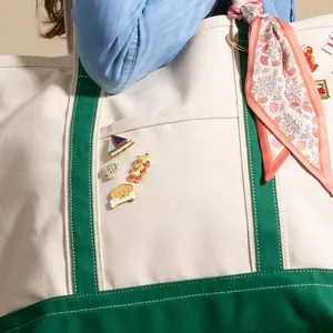 Detailed view of cute cartoon enamel pins decorated on a canvas tote bag pocket.