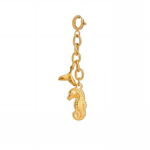 Detailopname van gouden zeepaardje en walvisstaart bedels aan een ketting met sluiting
