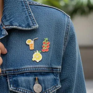 Detailed view of enamel pins featuring lemon and drink designs on a denim jacket.