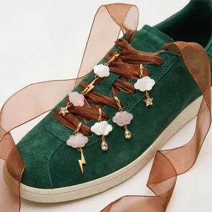 Detailed view of cloud and star shoe charms on a green suede sneaker