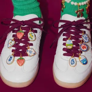 Gros plan de breloques de chaussures DIY colorées avec motifs de fruits et de cœurs.