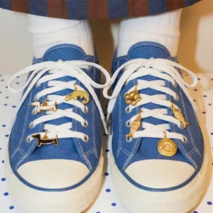 Close-up of cute animal enamel charms attached to white shoelaces on blue sneakers