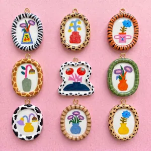 Group of nine hand-painted dopamine-style charms with animal print frames on pink background.