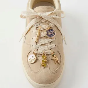 Detail view of DIY shoe charms including Yin Yang and Bonne Chance pendants on laces