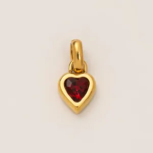 Detailed macro view of a gold-plated heart pendant featuring a faceted red birthstone
