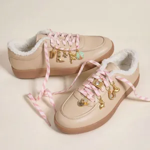 Close-up of gold DIY shoe charms featuring horseshoe and boot shapes on pink laces