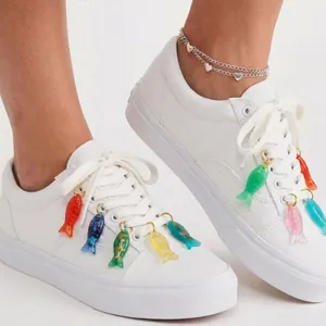 Dettaglio di ciondoli per scarpe a forma di pesci colorati su scarpe da ginnastica