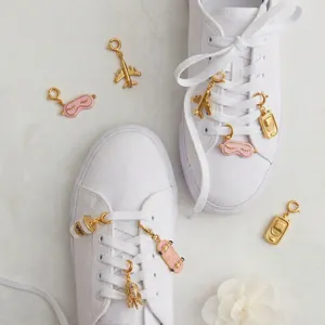 Detail of gold shoe charms with airplane and skateboard designs on white sneakers.