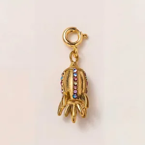 Close-up macro view of a golden rocket charm pendant adorned with multi-colored zircons.