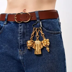 Close-up detail of golden graduation theme metal charms hanging on blue denim jeans