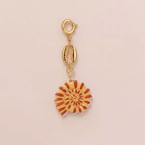 Detailed view of ocean-themed gold charm with spiral seashell and cowrie shell pendant