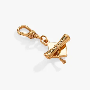 Close-up of a gold-toned graduation cap and scroll charm with GRADUATE engraving.