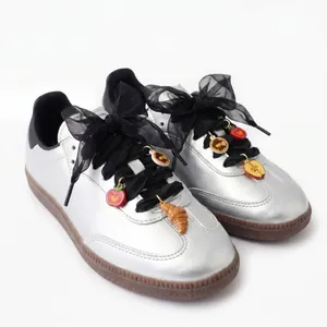 Detailed macro view of food-themed DIY shoe charms on silver sneakers with black ribbons