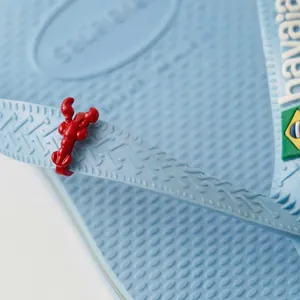 Detailansicht eines roten Hummer-Schuhanhängers an einem blauen Flip-Flop-Riemen.