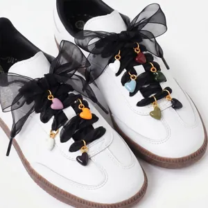 Detailed close-up of colorful heart-shaped shoe charms attached to black ribbon laces