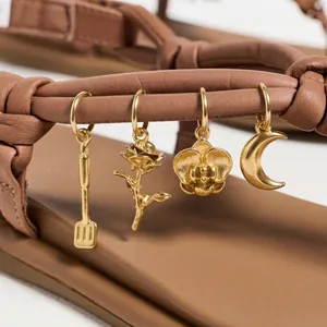 Detailansicht von vergoldeten DIY-Schuhanhängern aus Edelstahl an braunen Sandalen