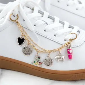Detalle de una cadena con dijes de acero inoxidable en cordones de zapatillas blancas