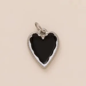 Primer plano de un colgante en forma de corazón plateado con esmalte negro liso