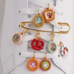 Close-up of colorful dopamine-style gold-plated safety pin shoe charms with cute pendants.