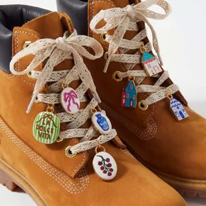 Close-up detail of colorful enamel DIY house and floral shoe charms on leather boot laces