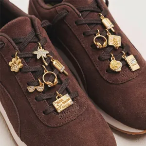 Detailed macro shot of gold-plated stainless steel DIY shoe charms on brown sneakers